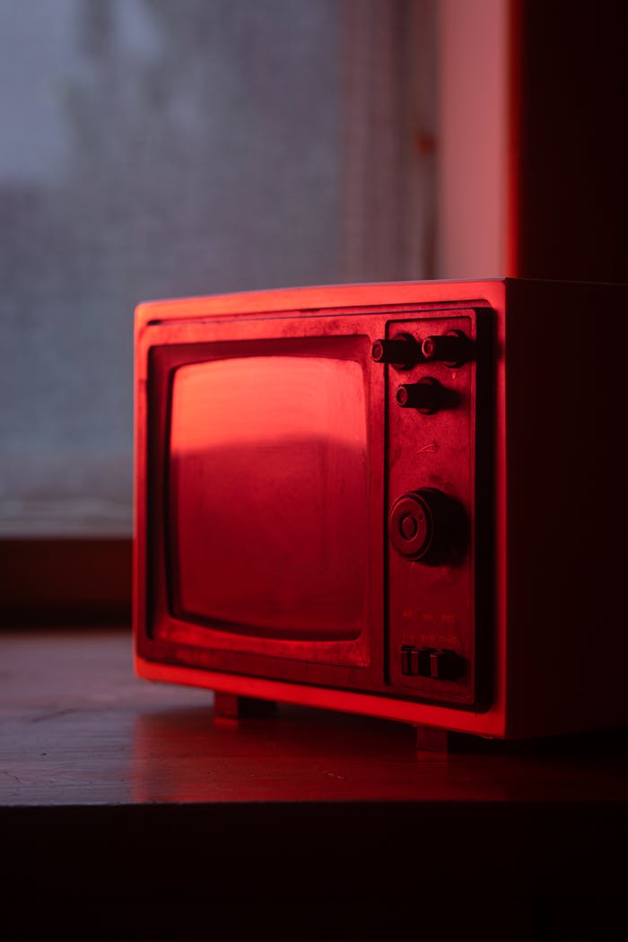 A vintage television set illuminated by red light, showcasing nostalgic technology indoors.